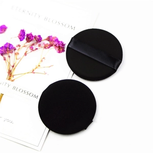 Detailed view of two black makeup puffs showing soft velvety texture and ribbon handle