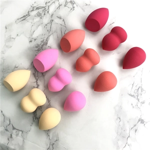 Macro shot of 12 multi-colored teardrop and gourd makeup sponges on white marble
