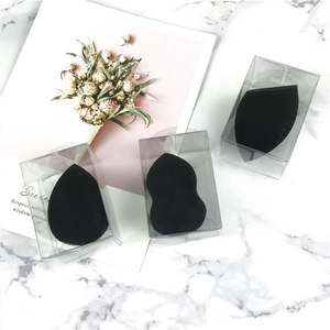 Three-piece black makeup sponges in transparent cases on a white marble surface