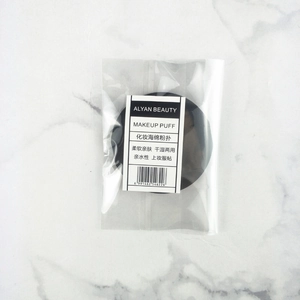 Detail of round black makeup sponge puff in retail packaging with marble background