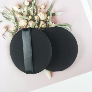 Detail of two premium non-latex black makeup puffs with a soft texture on pink background