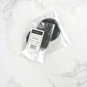 Macro detail of two black round makeup puffs in clear packaging on marble surface
