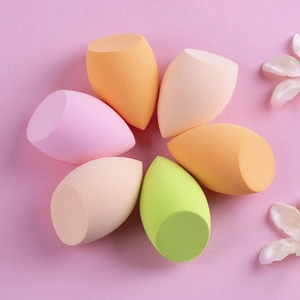 Detail view of colorful olive-cut makeup sponges arranged in a floral pattern on purple