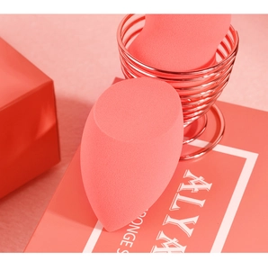 Detalle del set de esponjas de maquillaje rosa coral con un soporte de metal oro rosa