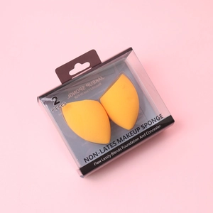 Detail of two slanted bright orange makeup sponges in a clear plastic storage box