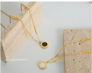 Detail of Roman numeral round pendants with black and white acrylic on gold paperclip chain
