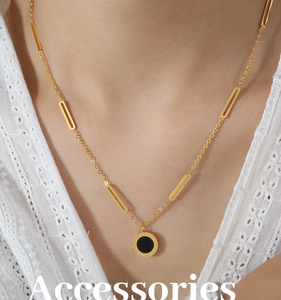 Close-up of gold titanium steel necklace with Roman numerals and black acrylic pendant