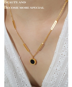 Detail of layered gold necklace with Roman numeral pendant worn on white lace fabric