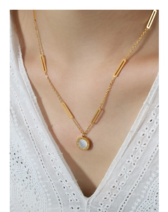 Close-up of a gold Roman numeral pendant necklace with white mother of pearl inlay
