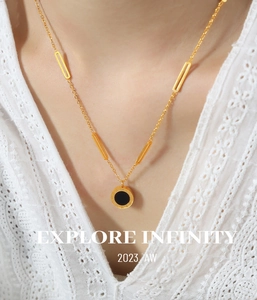 Close-up of golden Roman numeral pendant with black inlay on female model