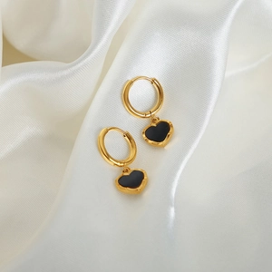 Boucles d'oreilles cœur dorées avec incrustation noire sur fond de soie blanche douce