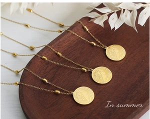 Detail of vintage gold-plated coin necklace with relief portrait on a wooden tray