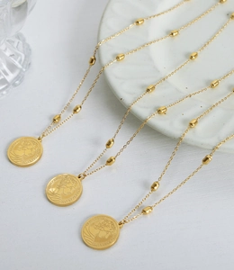 Detailed view of three gold coin necklaces with Elizabeth II portrait on bead chains