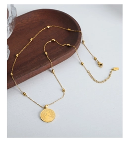 Detail of 18K gold necklace showing the cylindrical gold beads and queen coin pendant