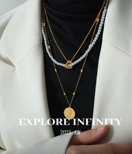 Detailed view of layered gold-plated necklaces with a vintage coin pendant and pearls