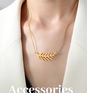 Detalle del collar con colgante de hoja de oro 18k en modelo con blazer blanco
