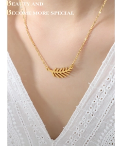 Vista detallada de un collar con colgante de hoja dorada en modelo con encaje