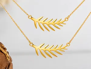 Detalle del collar con colgante de hoja dorada con diseño calado minimalista en acero titanio