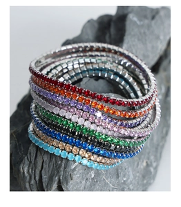 Detail von bunten Zirkonia-Tennisarmbändern auf einer grauen Natursteinbasis präsentiert
