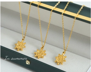 Vue détaillée de pendentifs gouvernail en or 18k sur de fines chaînes élégantes