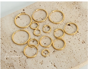 Detailed set of varied size gold hoop earrings displayed on a natural stone surface