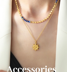 Gros plan sur collier double rang doré avec pendentif gouvernail et perles bleues