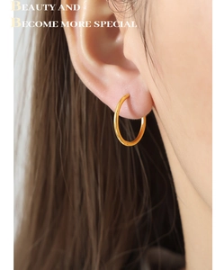 Close-up of minimalist gold-plated hoop earring with polished mirror finish on model