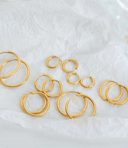 Macro shot of assorted diameter gold titanium earrings on white textured surface