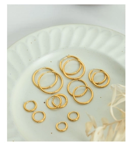 Detailed set of polished 18k gold hoop earrings in various sizes on a ceramic plate
