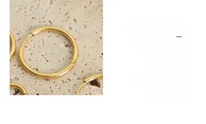 Close-up of gold chunky hoop earrings on a natural stone surface with warm lighting