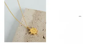 Gros plan du pendentif gouvernail doré avec gravure radiale sur un fond de pierre rustique