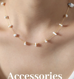 Detail of gold plated necklace with irregular white stones worn on model neck