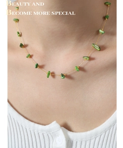 Detail of a minimalist gold-plated titanium necklace with irregular green stone beads