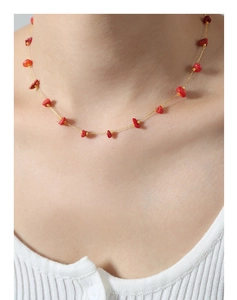 Close-up of irregular red stone pendant and gold-plated chain necklace on model