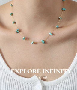 Detail of turquoise stones on a gold-plated thin chain necklace worn by a model