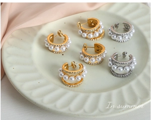 Détail de boucles d'oreilles créoles triple couche avec perles blanches et strass