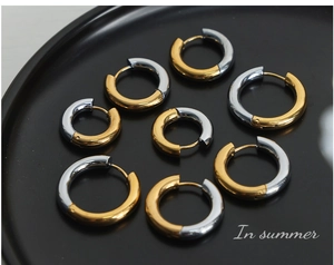Close-up of two-tone gold and silver geometric hoop earrings on black tray