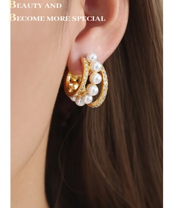 Gros plan sur la boucle d'oreille en titane doré avec perles et détails en cristal