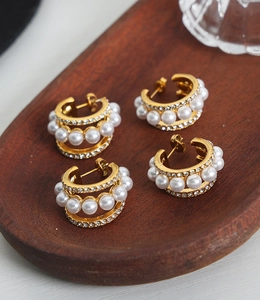 Détail de quatre boucles d'oreilles C dorées avec strass micro-sertis et perles sur bois