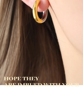 Close-up of geometric two-tone steel and gold plated thick hoop earrings on model
