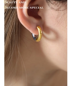 Detail of two-tone gold and silver hoop earrings featuring a polished geometric finish