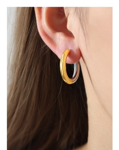 Close-up of dual-tone gold and silver hoop earrings on a model showing polished finish
