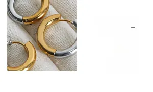 Close-up of two-tone geometric gold and silver hoop earrings on a textured linen background