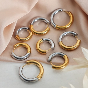 Minimalist gold and silver two-tone stainless steel hoop earrings on soft pink silk