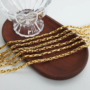 Polished gold plated geometric woven chain necklace displayed on a wooden tray