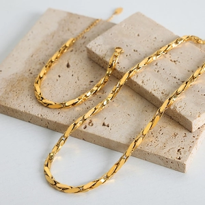Elegant gold plated geometric link chain necklace displayed on travertine stone stands