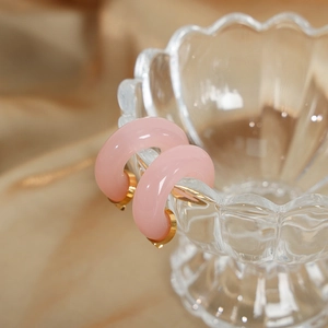 Pink resin C-shaped hoop earrings with gold metal interior in a minimalist style
