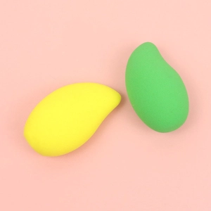 Macro view of mango-shaped makeup sponges in vibrant yellow and green on pink background