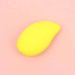 Macro shot of mango-shaped yellow makeup sponge on soft pink background texture