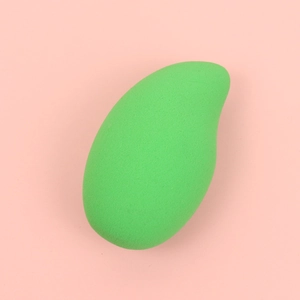 Macro detail of mango-shaped green makeup sponge with fine porous texture on pink base